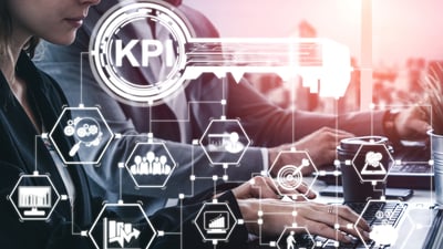 KPI key with indicator icons linked, background woman and man working on laptops