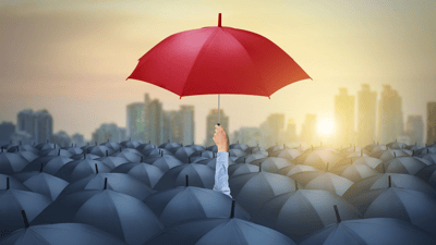 red umbrella above many black umbrellas cityscape background at sunrise