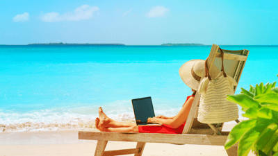 woman on a beach chair with computer light blue ocean