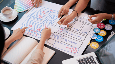 people designing a website with paper cutouts
