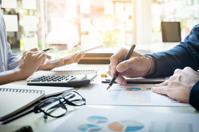 Two people working at a desk looking at charts and graphs.