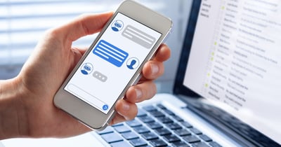 Person holding a mobile phone displaying a chat