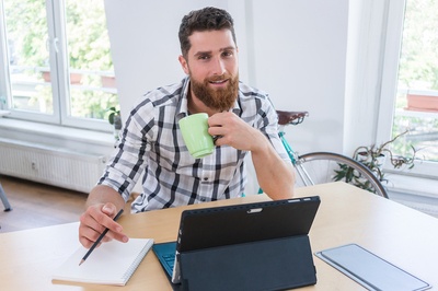 Man drinking a cup of coffee while working.