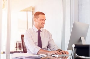 Man working on a desk top computer with a shirt and tie.