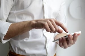 Man in a white dress shirt using his mobile phone.