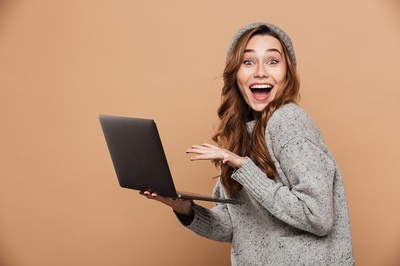 Woman appearing happy while holding a laptop.