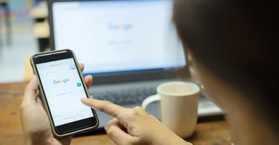 Person Searching on Google on a Phone and Desktop