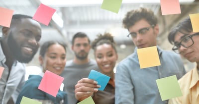 Group of people placing sticky notes on a board