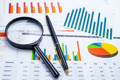 Papers with charts and graphs along with a magnifying glass.