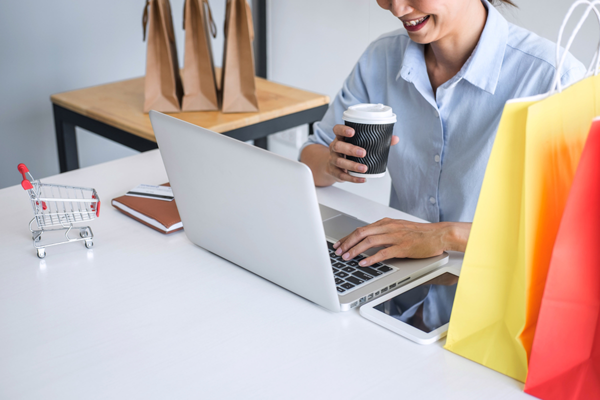 Woman drinking coffee while typing on a laptop.