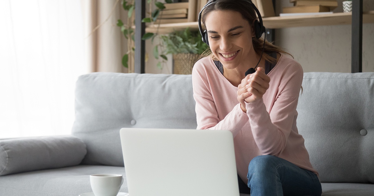 Smiling woman wearing a headset in front of a laptop.