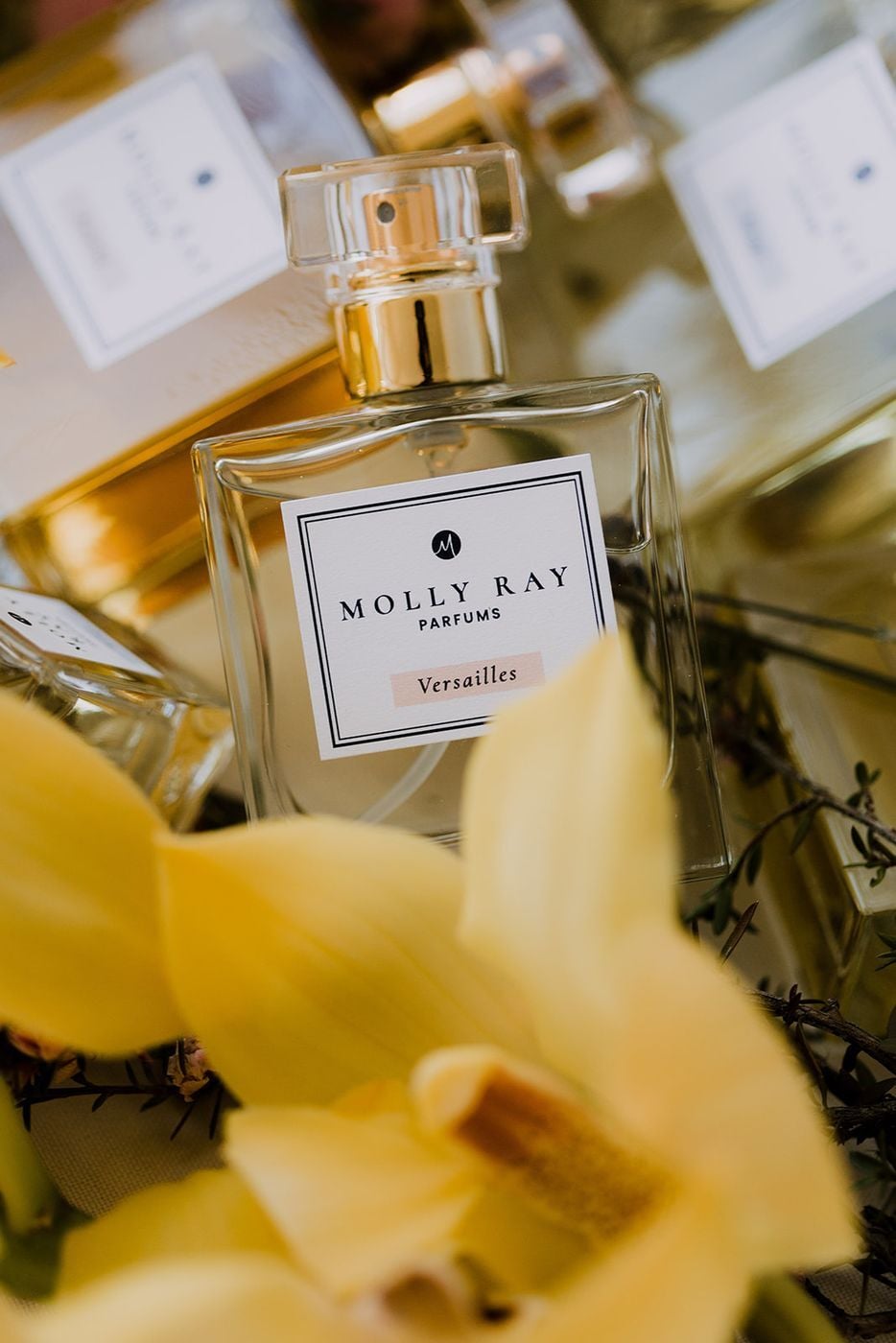Perfume bottle with yellow orchid petals in a styled flat lay